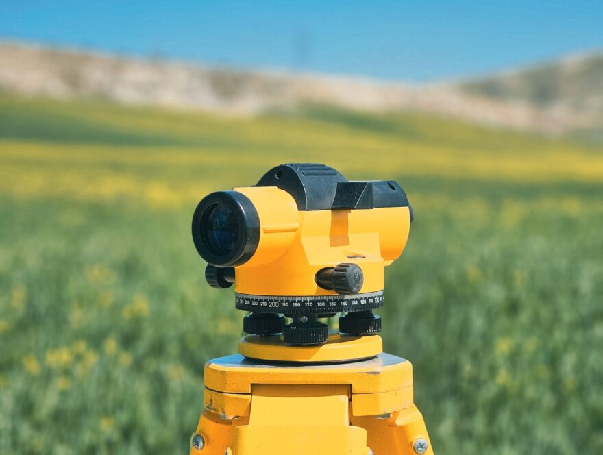 Surveying instrument on a tripod in a field — illustrative stock photograph