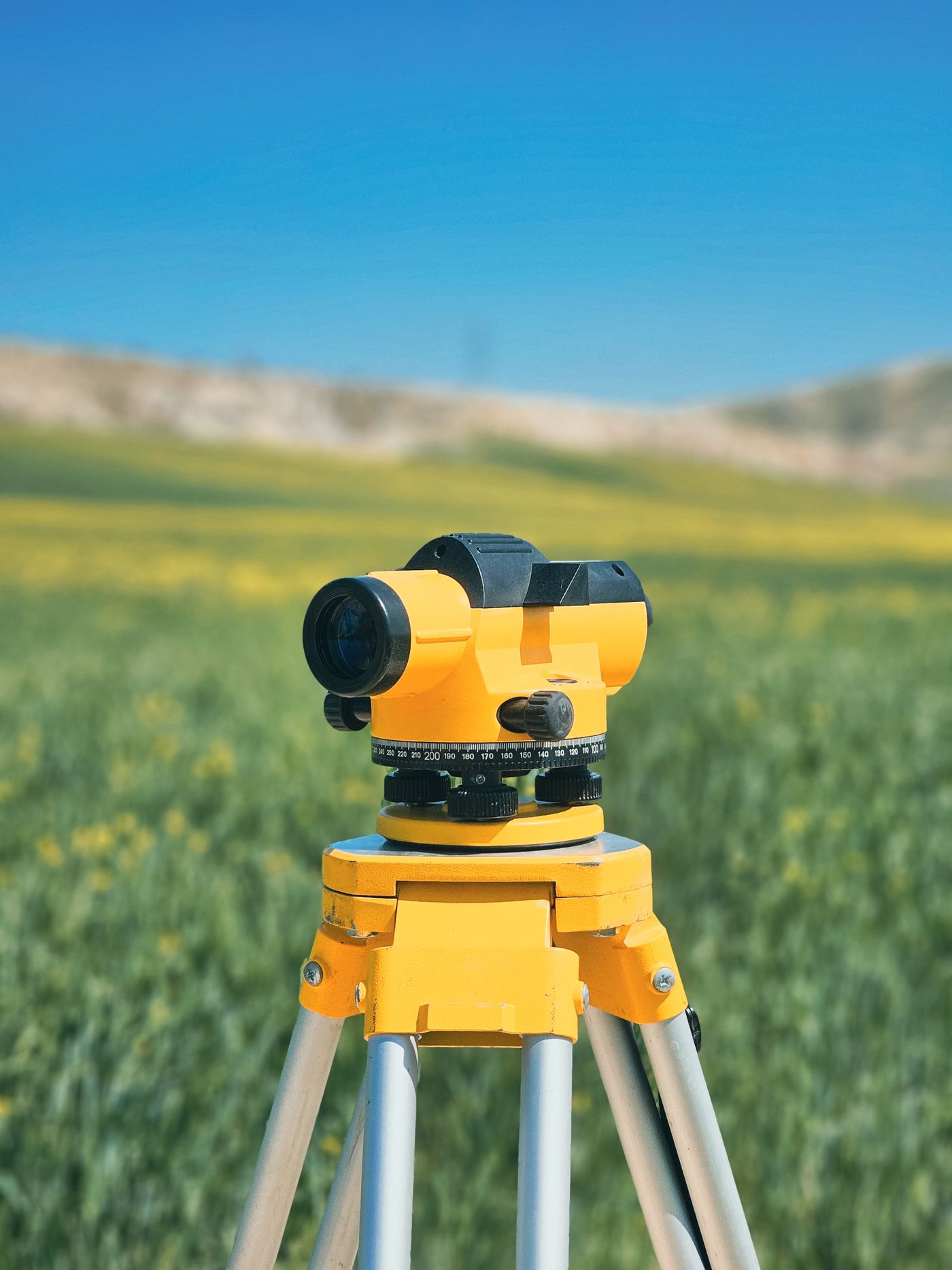 Surveying instrument on a tripod in a field — illustrative stock photograph